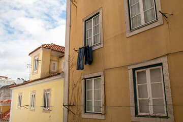 Fototapeta na wymiar Clothes drying on a rope in the sun, facade of an old yellow historical house, clotheslines in an old town in Lisbon, Portugal