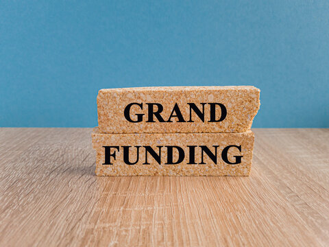 Grant funding symbol. Concept words Grant funding on wooden blocks. Beautiful wooden table light blue background. Business and grant funding concept. Copy space.