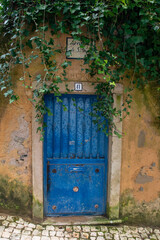 An old blue door, dirty peeling paint wall, vintage European rustic background 