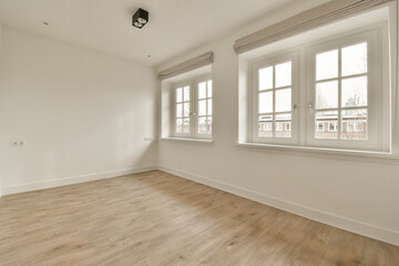 an empty room with white walls and wood flooring, there is a lamp on the wall in front of the window