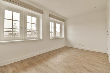 an empty room with white walls and wood flooring, there is a window in the wall to the right