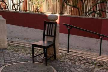 An empty wooden chair on a cobbled street of an old European city