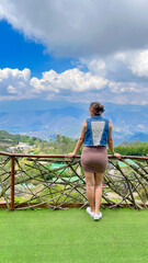 Young woman standing on the balcony and looking at the view of the mountains