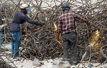 steel reinforcement scrap, welders cutting steel reinforcement scrap in the daylight