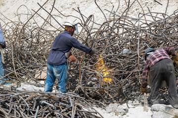 steel reinforcement scrap, welders cutting steel reinforcement scrap in the daylight