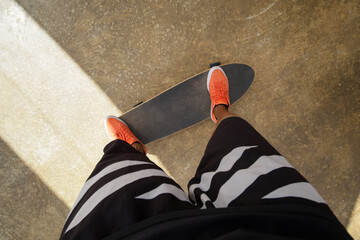 Point of view shot of skateboarder rides on skateboard in orange sneakers. - obrazy, fototapety, plakaty