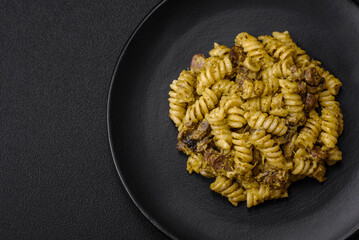Delicious fusilli pasta with green pesto sauce, with salt and spices