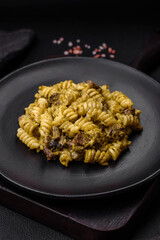 Delicious fusilli pasta with green pesto sauce, with salt and spices