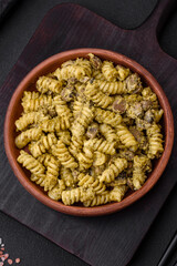 Delicious fusilli pasta with green pesto sauce, with salt and spices