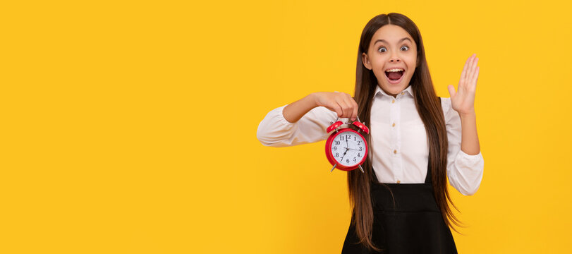 surprised kid in school uniform with alarm clock showing time on yellow background, time. Teenager child with clock alarm, horizontal poster. Banner header, copy space.