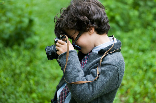 boy with glasses playing guitar in the garden taking pictures