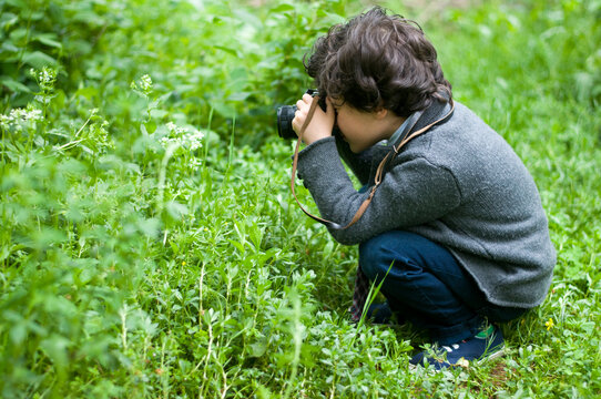 boy with glasses playing guitar in the garden taking pictures