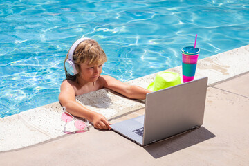 Child working with laptop on summer vacation holidays. Little freelancer using computer, remote working in swimming pool. Summer online technology.