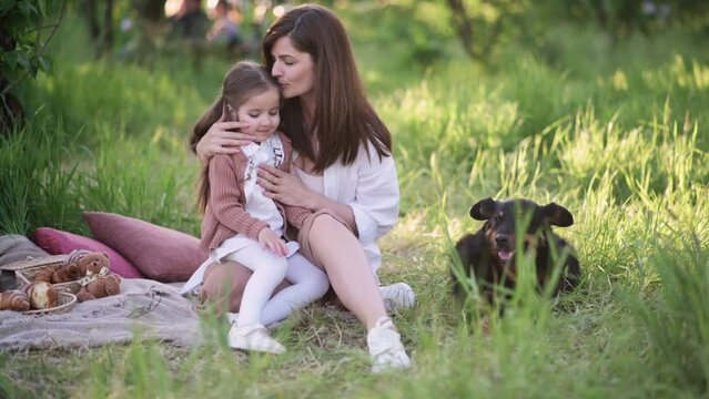 Mom and daughter on a picnic. A young mother hugs and kisses her daughter.