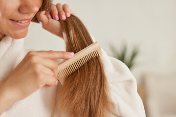 a young girl in a white coat takes care of her hair at home