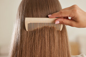 a young girl in a white coat takes care of her hair at home