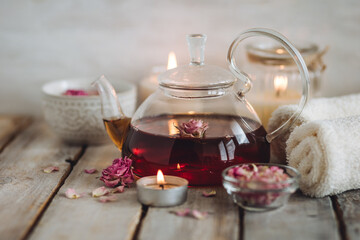 Aromatherapy. Bath salt, pure natural essential oils, floral rose extract. Spa treatment, skin care, relaxation with burning candles, herbal organic hot tea. Towel, wooden background