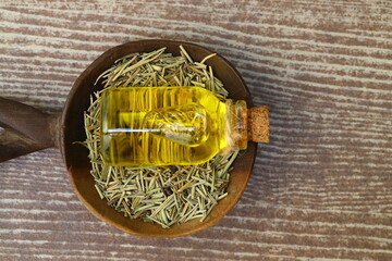 Dry organic background or texture of rosemary leaves. Healthy food concept . a wooden spoon with rosemary, a kind of green color and very fine sticks. leaning on a brown table.