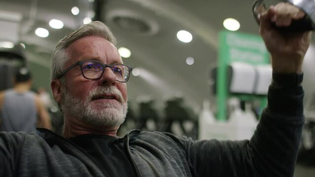 Senior man in his 60s working out at the gym on a lateral pulldown pulley machine