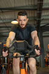 Homme sportif et barbu sur un vélo dans une salle de sport