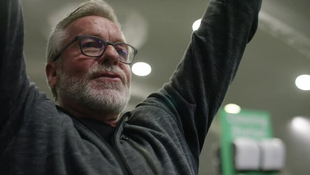 Senior male in his 60s finishing a set on a lateral pulldown machine at the gym