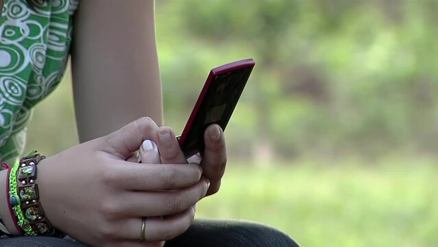 Young Girl Holding An Old Flip Cell Phone Outdoors. Close Up.