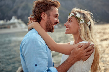 A young couple in love having romantic moments on the dock on the seaside. Love, relationship, holiday, sea - Powered by Adobe