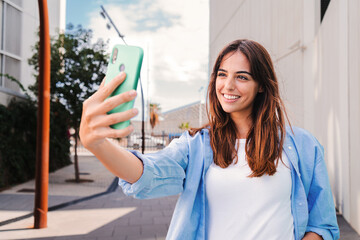 Happy young teenage female looking at camera and taking a selfie on smartphone showing a toothy...