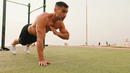 Middle aged muscular man doing push up exercises outdoors
