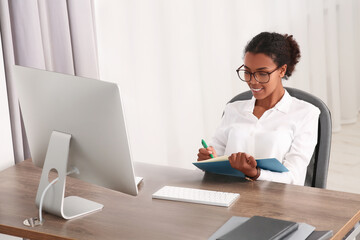 African American intern working with computer at table in office