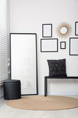 Stylish room interior with empty frames hanging on white wall and comfortable furniture