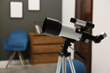 Tripod with modern telescope in stylish room, closeup