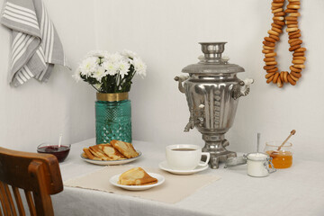 Vintage samovar, cup of hot drink and snacks served on table indoors. Traditional Russian tea...