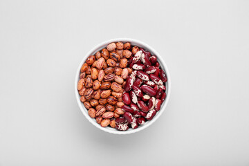 Different kinds of kidney beans in bowl on white background, top view