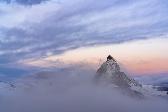 Clouds over Matterhorn peak emerging from mist at sunrise, Gornergrat, Zermatt, canton of Valais, Switzerland