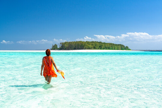 Woman admiring an exotic island standing in the crystal blue sea, Zanzibar, Tanzania