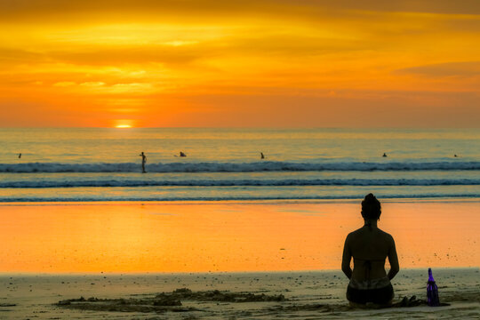 Girl and surfers silhouetted by sunset at this hip surf beach and yoga destination, Playa Guiones, Nosara, Guanacaste, Costa Rica