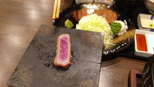 chopsticks grilling gyukatsu on hot plate Japanese food beef loin fried and let people cook their own beef level rare to well done