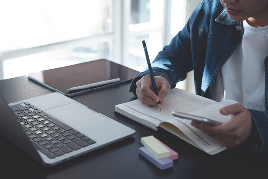 Event planner timetable agenda plan schedule event. Business woman checking planner on mobile phone, scheduling on calendar planner, laptop computer on office table. Calendar event planning