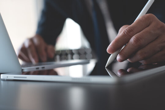 Businessman Using Stylus Pen Signing E-document Or Business Contract On Digital Tablet Via Mobile App With Laptop Computer On Office Desk. E-signing, Electronic Signature, Business Concept