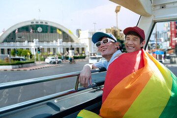 LGBTQ couple with rainbow flag spending time together traveling on bus tour, Hualampong, popular...
