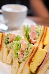 Japanese sandwich with omelette, ham, tomato, lettuce, cucumber and sauces in a cafeteria.