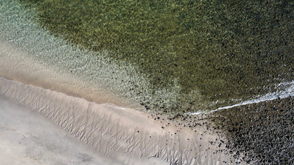 Drone photo of beach borderline with sand pattern and clear water. 