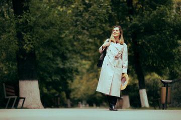 Beautiful Woman Wearing a Stylish Beige Trench Coat. Pretty and stylish lady in a classical outfit walking on an alley 
