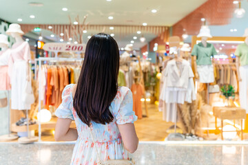 Young Asian woman choosing clothes in clothing store at the mall, woman shopping lifestyle concept