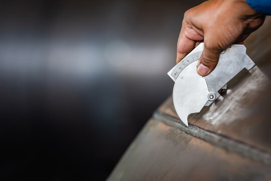 QC Technician inspector using welding gauge inspection butted weld on plate steel structure in industry fabrication factory. NDT