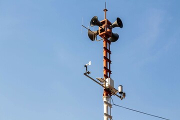 Tsunami warning pole located on the beach with a blue sky background.