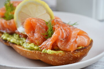 Avocado toast with salmon, lemon,  and dill on the plate.