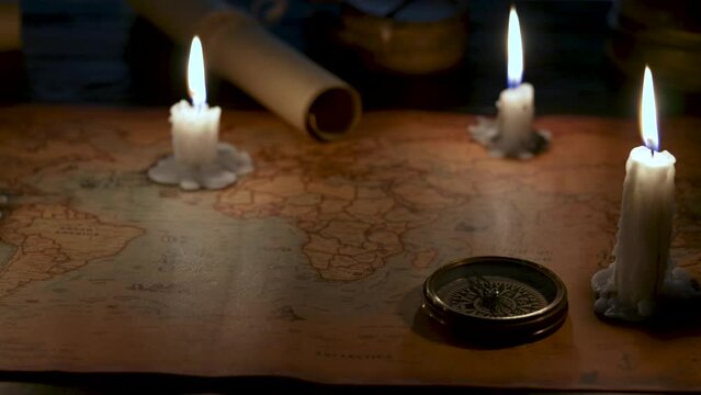Old vintage retro compass on ancient map. Composition illuminated by candles.
