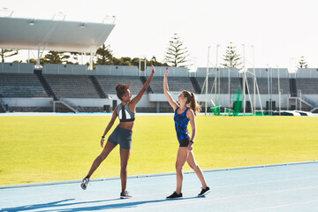 Woman, team and high five on stadium track for running, exercise or training together in athletics outdoors. Women touching hands in celebration for exercising, run or winning in teamwork and fitness